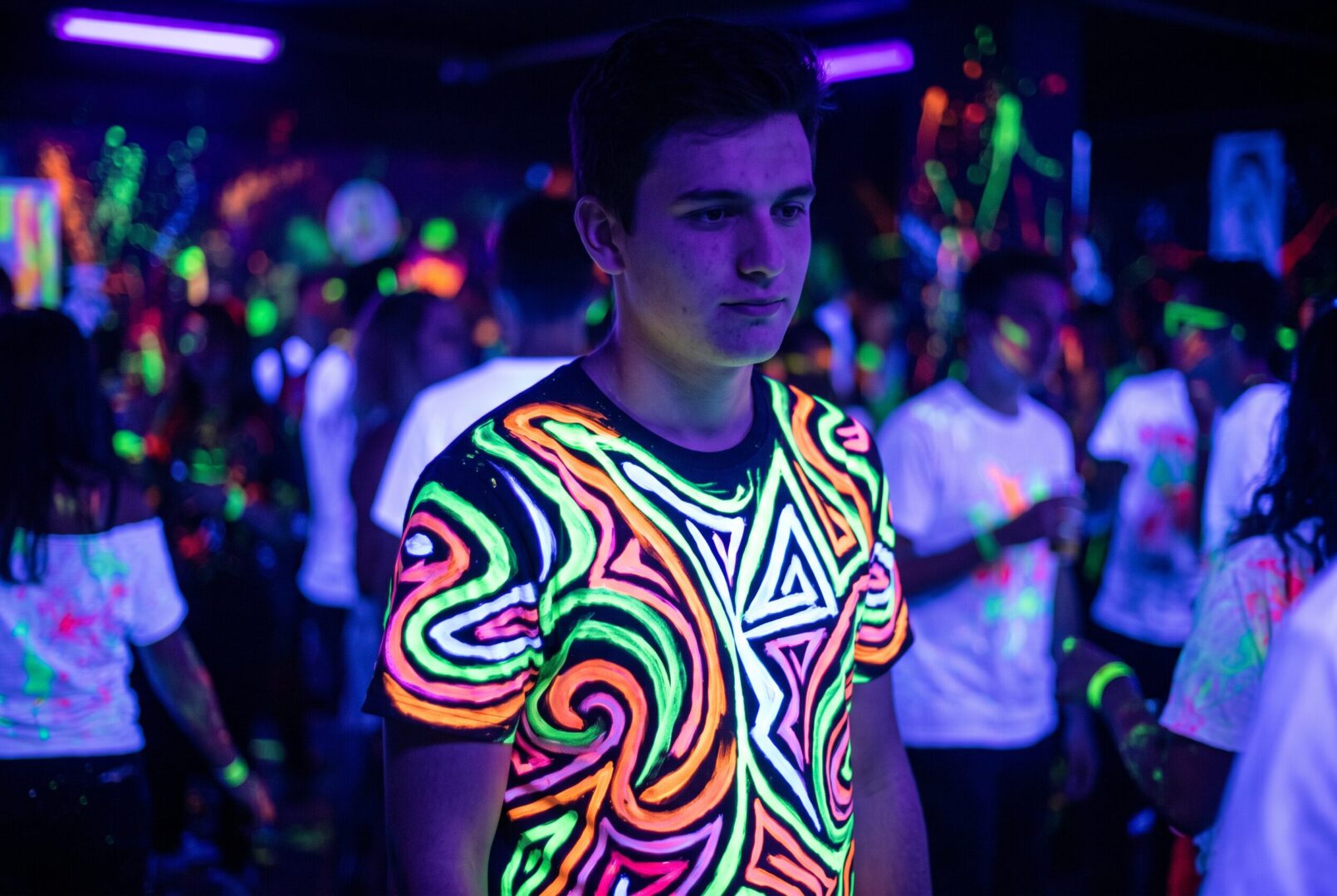 Man in a glowing neon t-shirt under UV blacklight at a rave