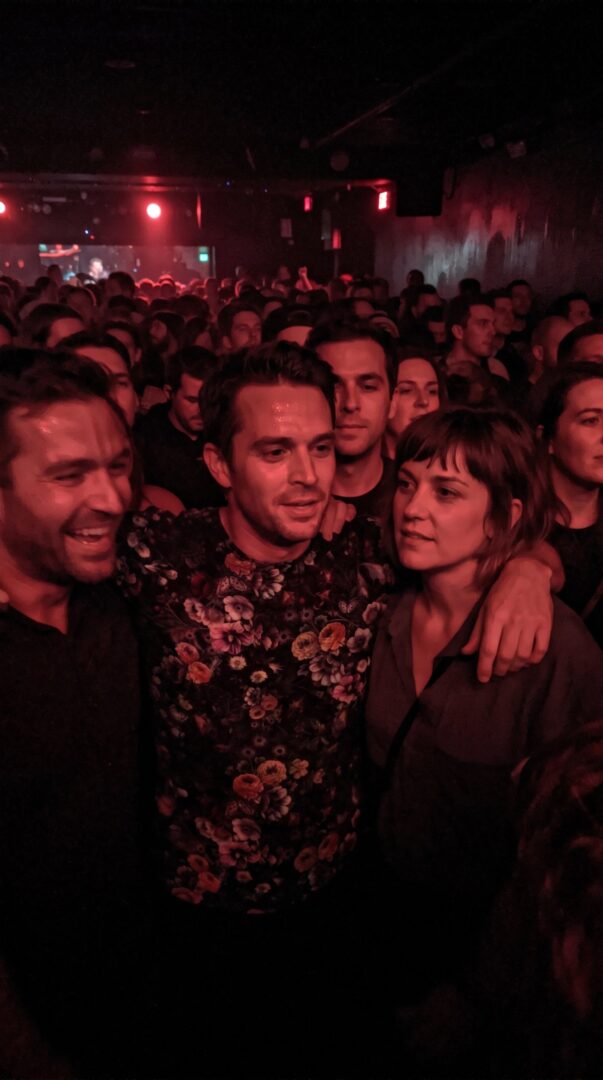 Packed gig crowd under red stage light with printed t-shirts visible